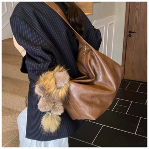 Dettaglio borsa tote marrone in pelle con ciondolo a forma di animale e cerniera dorata