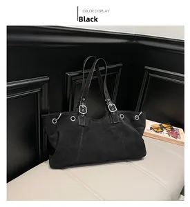 Detail of black suede tote bag featuring silver eyelets and buckle accents on leather bench