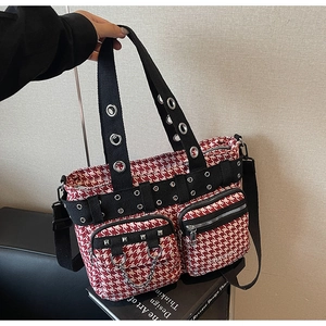 Detail of red and white houndstooth tote bag featuring silver rivets and metal chain accents