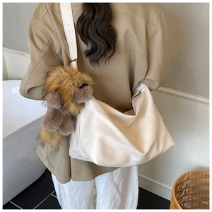 Dettaglio della grande borsa hobo bianca con ciondolo in peluche marrone sulla tracolla
