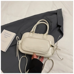 Detail of white PU Boston bag showing golden hardware and side bow ribbon accents