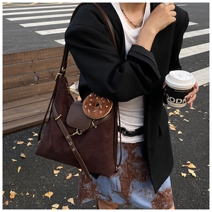 Street style shot of large brown suede tote bag with donut charm on city street