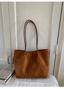 Detail of minimalist brown suede tote bag with double straps and vintage stitching finish