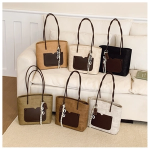Multiple textured tote bags with leather pockets and tassel detail on a cozy sofa