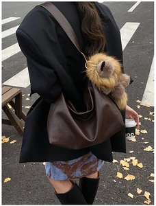 Dettaglio di una grande borsa hobo marrone vintage con texture morbida e ciondolo a orso