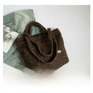 Detailed top view of a brown plush tote bag with a metal heart buckle on white background
