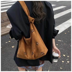 Détails du motif floral découpé au laser sur le sac cabas en daim marron porté