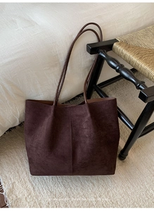 Detail of minimalist dark brown suede tote bag with slim handles in a retro home setting
