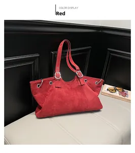 Detail of red suede tote bag showing silver metal ring and adjustable strap texture