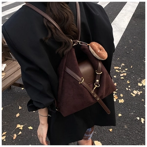 Detail of suede backpack with brown leather straps and a decorative donut pendant charm