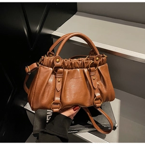 Detail showing vintage brown pleated baguette bag with metal rings and leather strap details