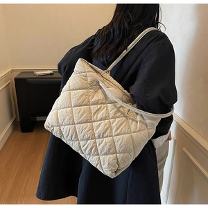 Detailed look at the beige quilted tote bag with diamond stitching on a female model