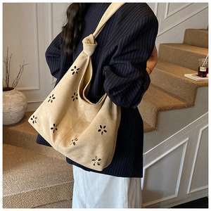 Détail de fleurs découpées au laser sur un sac fourre-tout en daim beige à bandoulière nouée