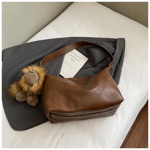 Dettaglio della borsa tote vintage marrone con un grande ciondolo a leone di peluche