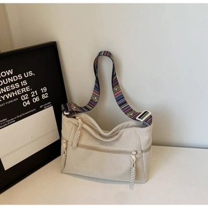 Detail of ivory corduroy tote bag with ethnic style colorful shoulder strap and zipper