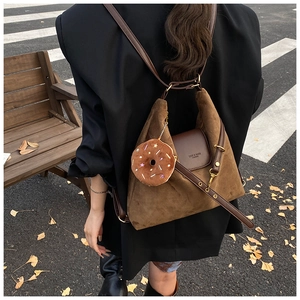 Brown suede tote bag with donut plush charm shown in an urban street setting