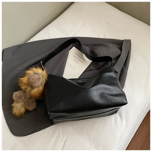 Dettaglio della borsa tote in pelle nera con trama litchi e ciondolo in peluche marrone