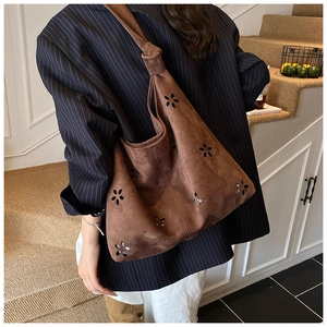 Détail des motifs floraux découpés au laser et sangle nouée du sac en daim brun