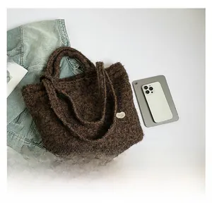 Flat lay of brown fluffy tote bag with denim jacket and magazine on white backdrop