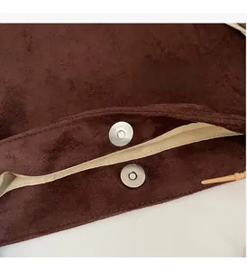 Detail of silver magnetic clasp on brown suede tote bag with soft fabric lining interior