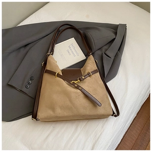 Detailed close-up of khaki suede tote bag with brown leather trim and golden metal hook