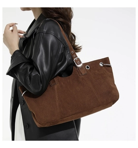 Side view of large brown suede tote bag with metal buckles and wide shoulder strap