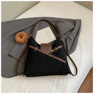 Detail of suede tote bag featuring brown leather straps and gold buckle accents