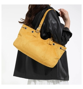 Side view of yellow suede tote bag with adjustable strap and silver metal hardware details