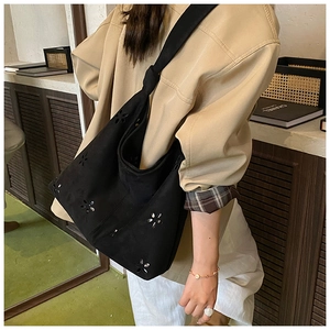 Détail du motif floral découpé au laser sur un sac cabas en daim porté par un mannequin