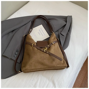 Macro shot of brown suede tote bag featuring a leather strap and gold metal hook detail