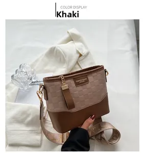 Detail of khaki bucket bag featuring checkerboard embossing and wide jacquard strap