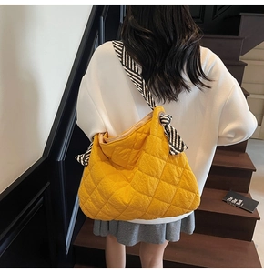 Yellow quilted nylon tote bag featuring a striped shoulder strap and decorative bow