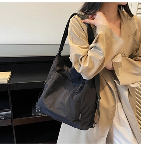 Vue détaillée du sac cabas en nylon plissé noir avec large bandoulière et étiquette