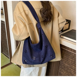Détail du sac cabas en daim bleu marine avec motifs de fleurs et bandoulière nouée