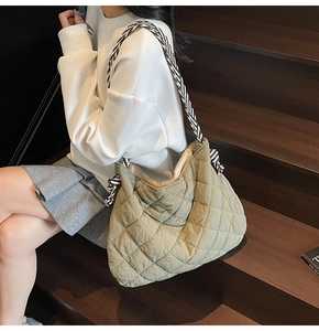 Detail of olive green quilted tote bag with zebra print strap on wooden stairs