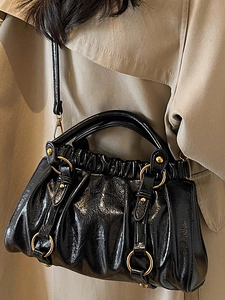 Chic black glossy pleated dumpling bag with golden hardware and adjustable strap