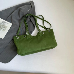 Detailed macro view of green suede tote bag with silver buckle and metallic grommets