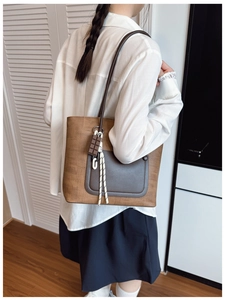 Brown woven texture tote bag with leather pocket and chocolate charm on model's shoulder