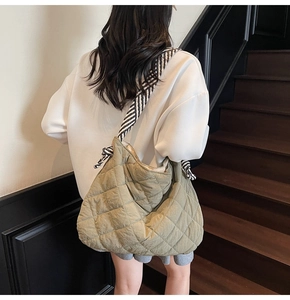 Rear view of a model wearing the olive green quilted tote bag with a striped shoulder strap
