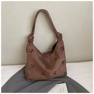 Détails de sac cabas en daim marron avec motifs floraux ajourés et découpes au laser