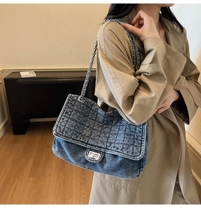Detail of blue quilted denim shoulder bag with silver metal chain and twist lock