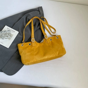 Detail of adjustable silver buckle and matte texture on yellow faux suede tote bag