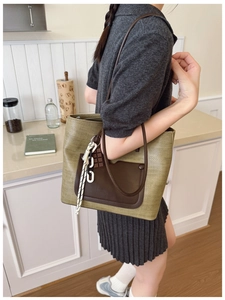 Detail of olive green woven tote bag with brown leather pocket and textured shoulder strap