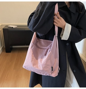 Détail du grand sac à bandoulière rose en tissu texturé avec étiquette de marque tissée