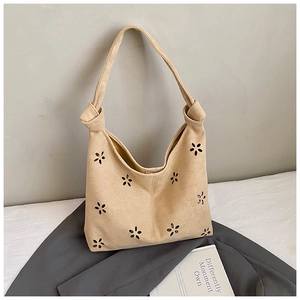 Gros plan du sac fourre-tout en daim beige avec fleurs découpées et bandoulière nouée