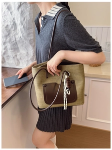 Detailed view of an olive green woven canvas tote bag with a brown leather front pocket