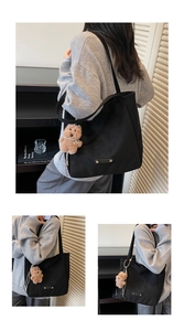Detail view of a black canvas tote bag with a brown teddy bear charm and leather logo patch