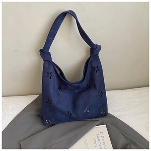 Détail du sac hobo en daim bleu foncé avec fleurs découpées et sangle à nœuds