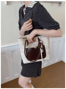 Detail shot of a beige woven tote bag with brown leather pocket and a decorative side rope