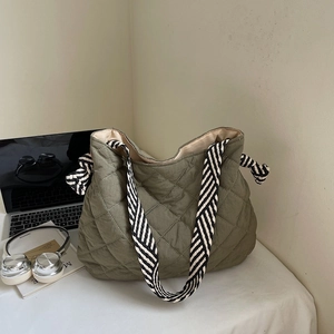 Detailed macro view of army green quilted tote bag with striped woven strap and large capacity